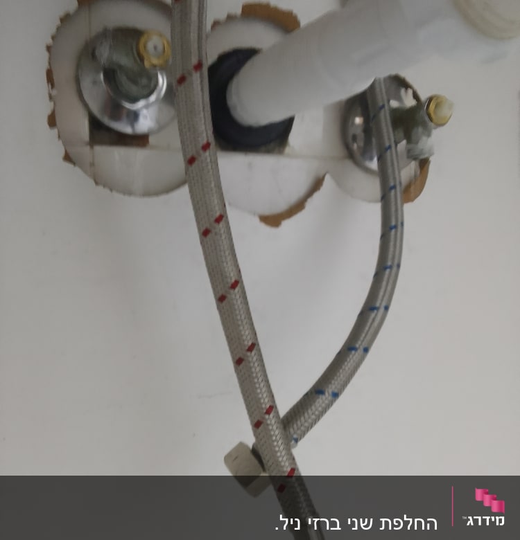 צינורות מים מתכתיים מחוברים לברזים מתחת לכיור